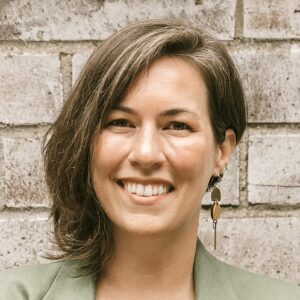 A Caucasian woman in her thirties with medium length brown hair smiles.